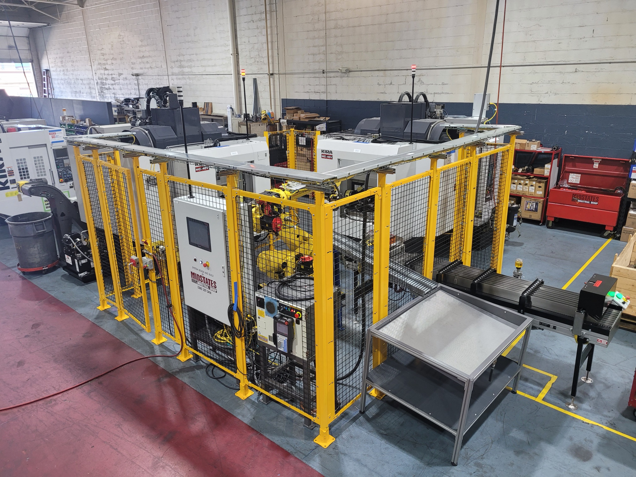 Completed dual-op machining and automation cell with robot, conveyors, and fenced safety envelope.