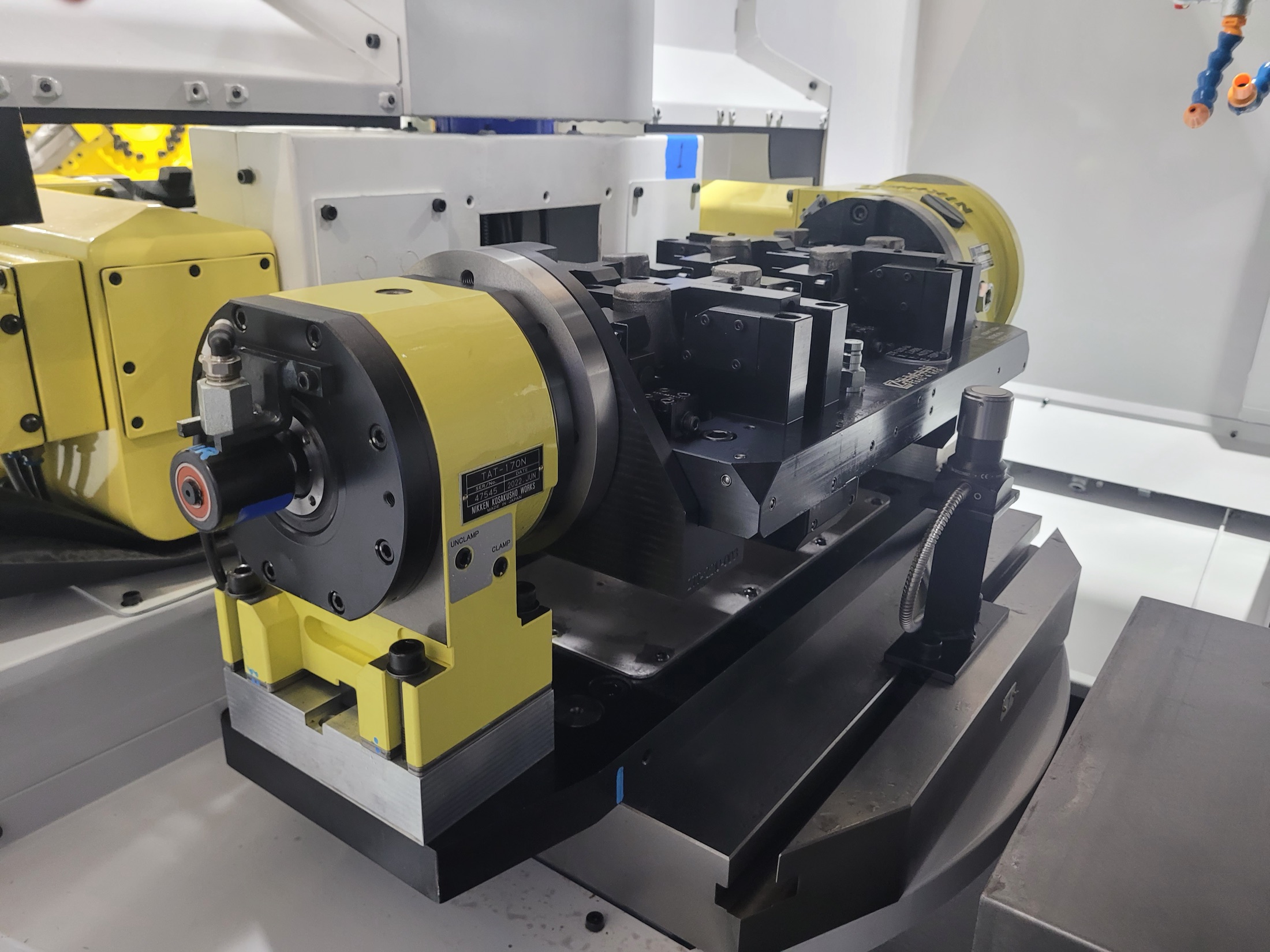 Rotary fixture assembly inside machine envelope for dual-op machining.